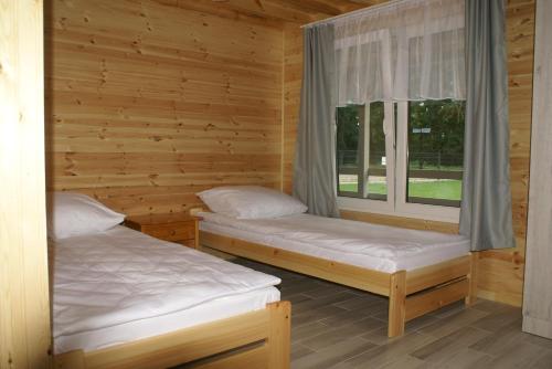波别罗沃DIUNA Domki Letniskowe的木间设有两张床,设有窗户