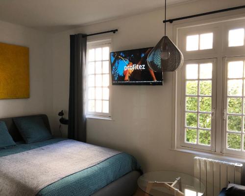 多维尔Deauville centre, plage, casino et hippodrome的卧室配有一张床,墙上配有电视。