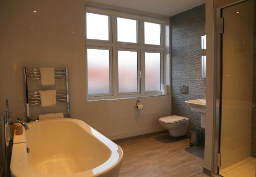 西默西梅尔西胜利旅馆的带浴缸、卫生间和窗户的浴室