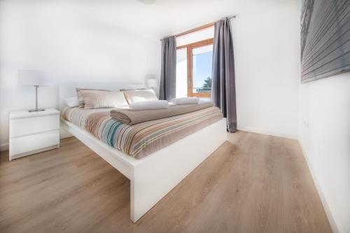 坎布里尔斯Agaró Cambrils Apartments的白色的卧室设有一张大床和一个窗户