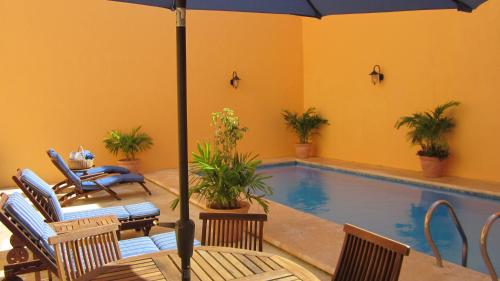 坎佩切卡斯特尔玛酒店的游泳池配有遮阳伞和椅子以及一张桌子。