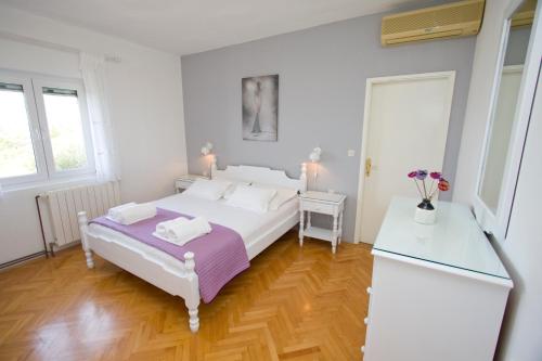 马卡尔斯卡Apartment Glavina with private pool的白色卧室设有白色的床和木地板