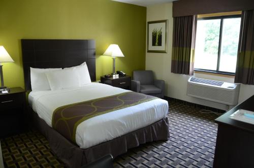 West Burlington西伯灵顿阿美瑞辛酒店的酒店客房带一张大床和一把椅子