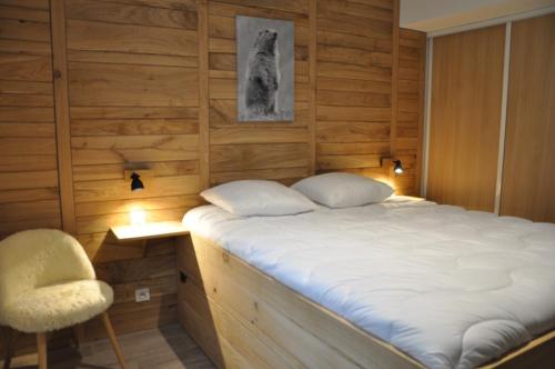 拉姆吉Appt Le Caribou/La Mongie的一间卧室配有一张大床和一把椅子