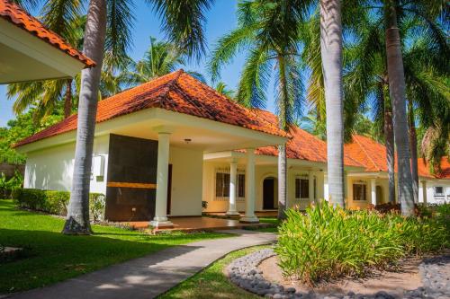 San LuisPato Canales Hotel & Resort的一座拥有橙色屋顶和棕榈树的房子