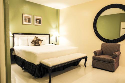 IlaganDreamwave Hotel Ilagan的一间卧室配有一张床、一把椅子和镜子