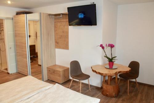 圣吉尔根Echt Heimat Apartments的一间设有桌椅和墙上电视的客房