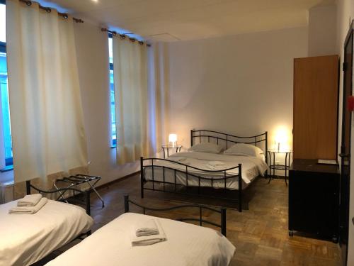布鲁塞尔阿伯丁酒店的带3张床和2张桌子及窗户的房间