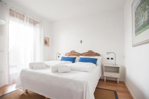 加尔达湖滨Casa Davide的白色卧室配有白色大床和蓝色枕头