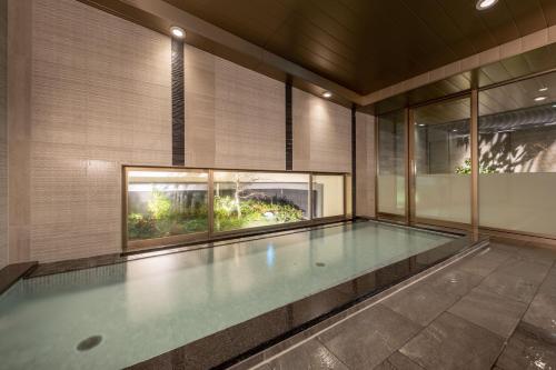 名古屋Nishitetsu Hotel Croom Nagoya的一座有窗户的建筑中的空游泳池