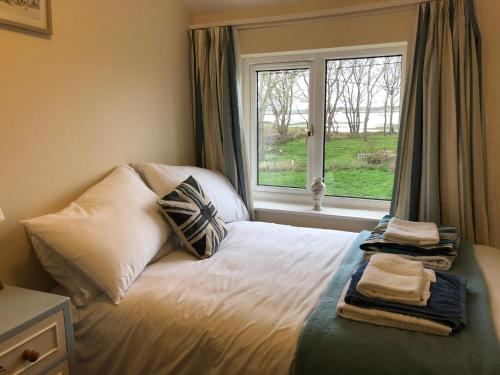 奥尔德堡Marsh View Cottage, Aldeburgh的卧室配有带枕头的床铺和窗户。