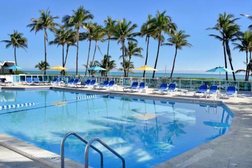 迈阿密海滩迈阿密海滩海岸套房公寓式酒店的一个带椅子的游泳池,棕榈树