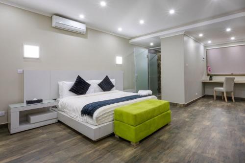 卢萨卡Fallsway Suites的一间卧室配有一张床和一个绿色的搁脚凳