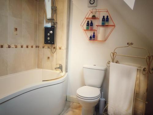 NeedwoodThe Loft at Peake’s retreats的浴室配有卫生间、浴缸和水槽。