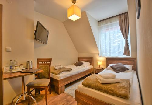赖曼瑙-兹德鲁伊苏珊娜Spa旅馆的酒店客房设有两张床、一张桌子和一台电视。