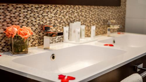 宰拉勒达AZ Hôtels Zeralda的浴室设有两个水槽和一箱橙玫瑰花