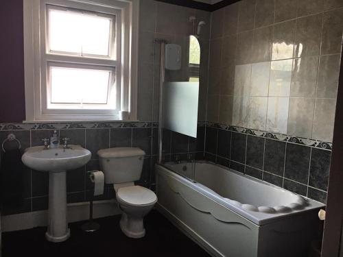 南安普敦Glenmore Guesthouse的一间带水槽、浴缸和卫生间的浴室