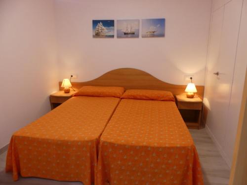 萨洛Zeus Alexis的一间卧室配有一张带橙色床单和两盏灯的床。