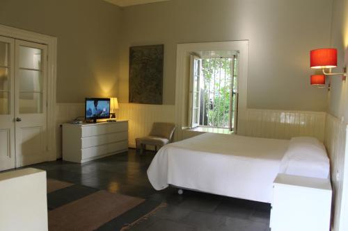 Malloa马约阿广场酒店的一间卧室配有一张床、一台电视和一个窗口