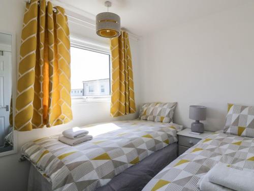 大雅茅斯Sunbeach Chalets的卧室内的两张床,配有黄色和灰色窗帘