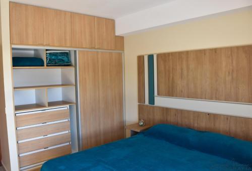圣拉斐尔Malvinas Departamentos的一间卧室配有一张蓝色的床和木制橱柜。