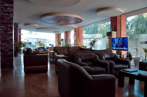埃尔比勒法瑞克酒店的一间设有皮椅和平面电视的等候室