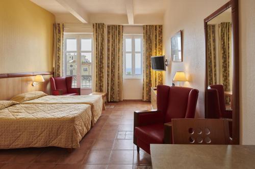 圣拉斐尔Residence Vacances Bleues le Mediterranée的酒店客房配有2张床、椅子和电视。