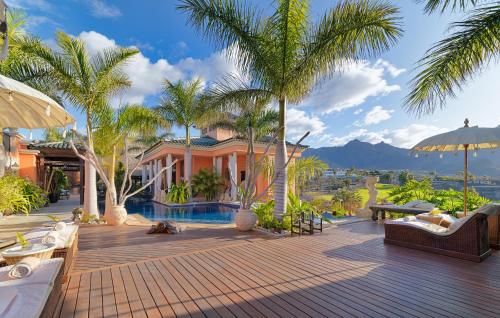 阿德耶Royal Garden Villas, Luxury Hotel的一座带棕榈树甲板的房子