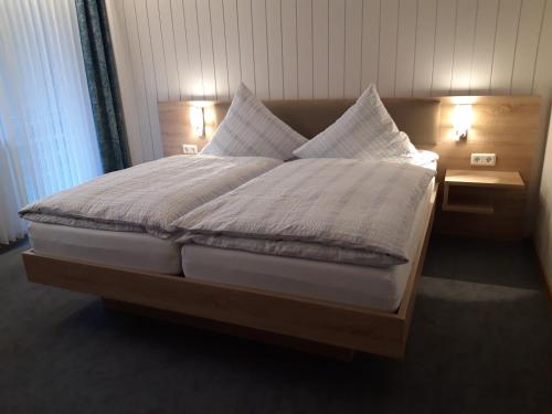 维林根Pension Ferienwohnungen Rosenschlösschen的一张带白色床单和枕头的床