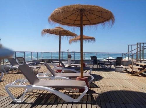 克莉丝蒂娜岛Islantilla-Apartamento con piscina y garaje en primera línea de playa的海滩上的一组椅子和遮阳伞