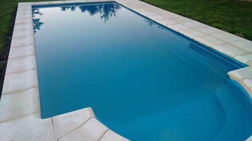 奥拉瓦里亚Casa Quinta Las Pintas的蓝色的游泳池,水中倒映着一棵树