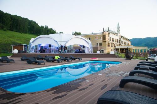 曼哲罗克Altai Palace Hotel的一个带椅子的游泳池和一个位于后面的帐篷