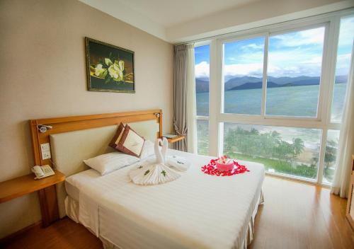 芽庄龙竹酒店的一间卧室设有一张大床和大窗户