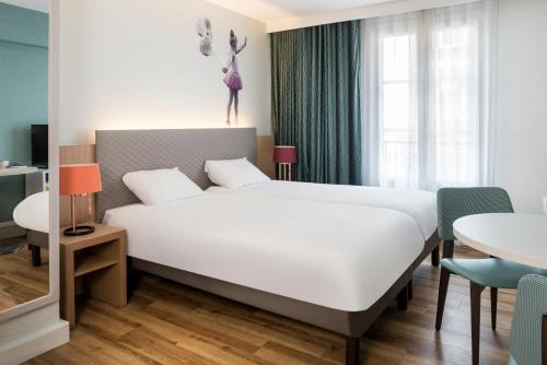 巴黎巴黎蒙马特爱达格公寓式酒店的卧室配有一张白色的大床和一张桌子