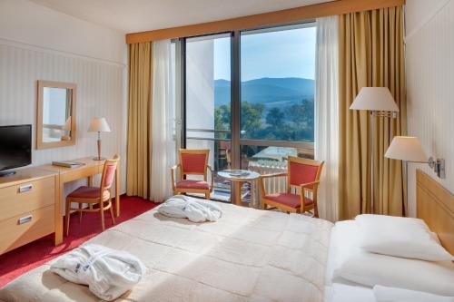 皮耶什佳尼Ensana Esplanade的酒店客房,配有一张床、一张桌子和椅子