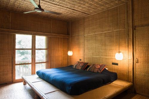 湄登丽苏旅馆的一间卧室设有一张大蓝色的床和窗户