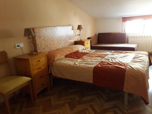 锡古恩萨Apartamento Turístico Sigüenza的一间卧室配有一张床、一张沙发和一把椅子