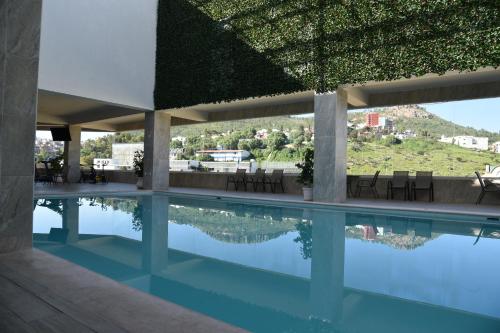 萨卡特卡斯唐米格尔酒店的一座带绿色屋顶的建筑中的游泳池