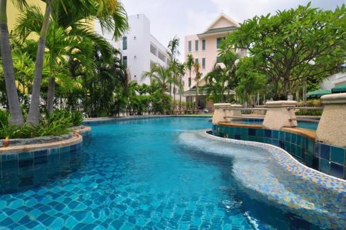 卡伦海滩Baan Karonburi Resort - SHA Plus的拥有蓝水和棕榈树的度假村的游泳池