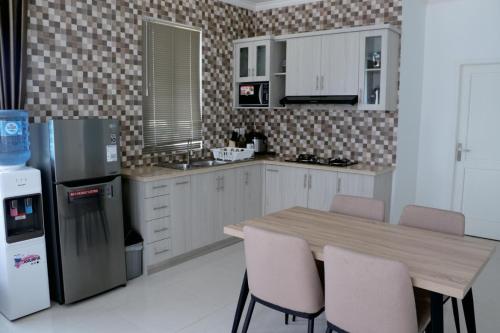 普卡Diyar Villas Puncak F4/8的厨房配有桌椅和冰箱。