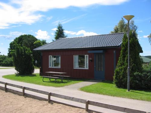ÄtranÄtrans Stugby & Fritidsanläggning的一间红色小屋,前面设有野餐桌