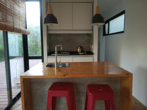 拉佩德雷拉Agua y Manto的厨房设有木岛和两个红色凳子