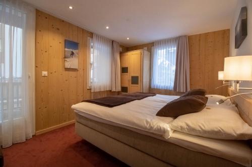 采尔马特阿尔卑斯洛奇酒店的一间卧室设有一张大床和两个窗户。