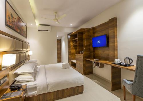 科钦Aura One Hotel的一间卧室配有一张床、一张书桌和一台电视。