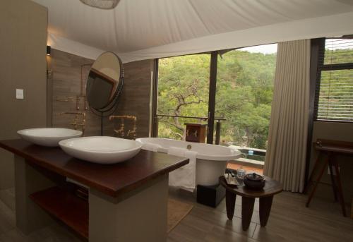 威尔吉旺登禁猎区Inzalo Safari Lodge的一间带两个盥洗盆、浴缸和窗户的浴室