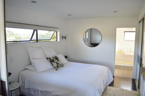 哈海Hahei Beach Apartment的卧室配有白色的床和镜子