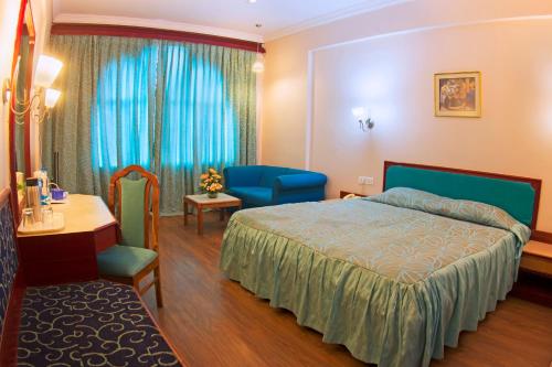 迈索尔Maya's Kings Kourt的酒店客房配有一张床铺和一张桌子。