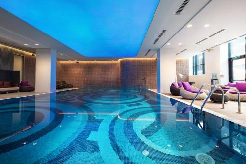 阿拉木图Novotel Almaty City Center的酒店大堂的游泳池,拥有蓝色的天花板