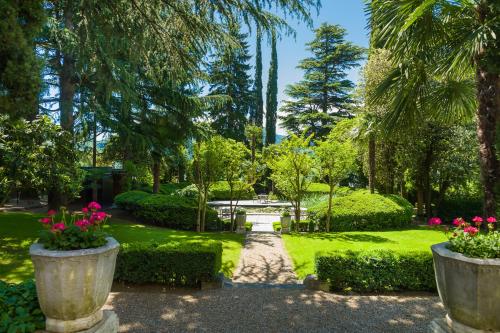 梅拉诺Villa Eden a member of Leading Hotels of the World的一个大水泥锅里种有粉红色花的花园