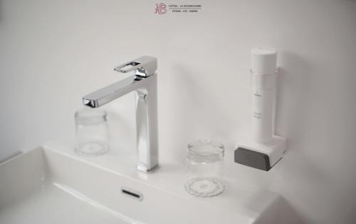 埃维昂莱班布尔格尼酒店的浴室水槽配有水龙头和2个玻璃杯